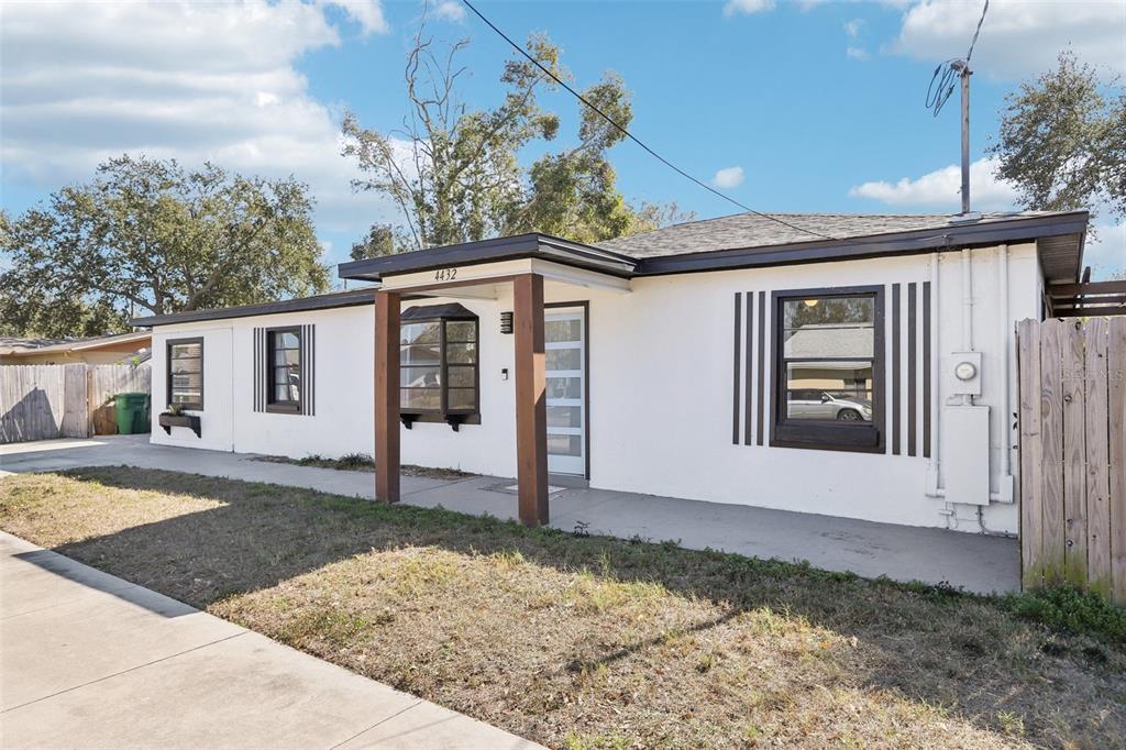 A single-story white house with a flat roof, brown trim, and a concrete walkway — 4432 W MCCOY STREET, TAMPA, FL