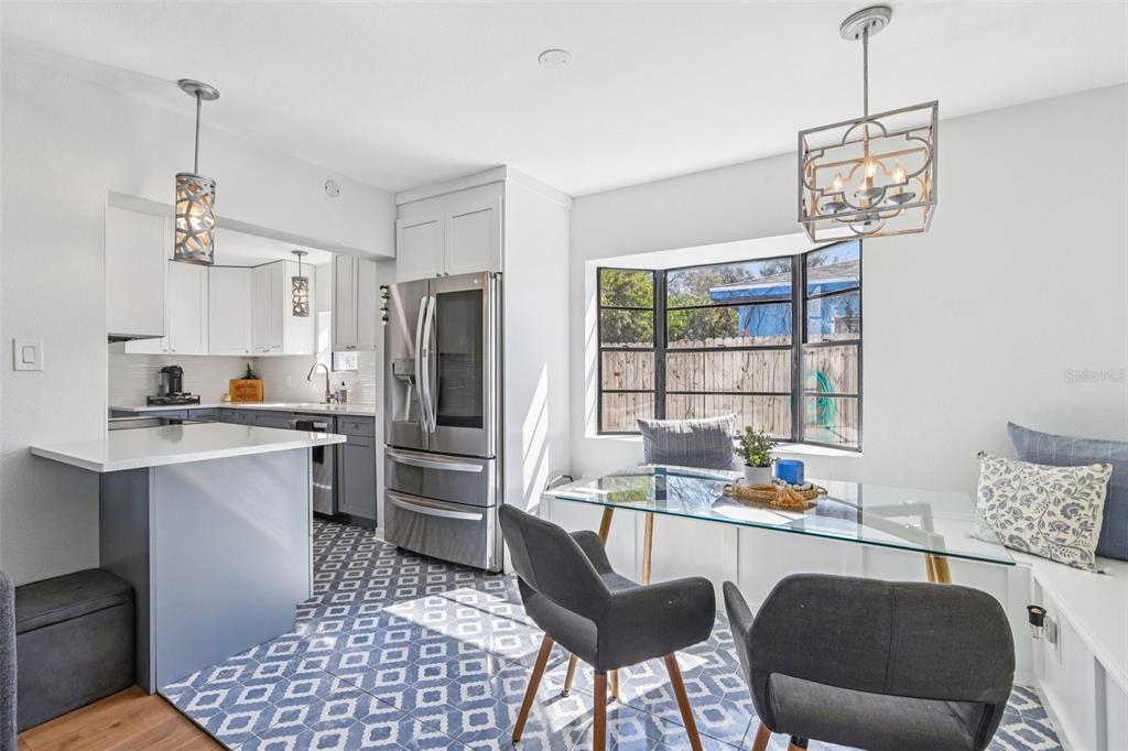 A kitchen and dining area features white cabinets, stainless steel appliances, and a glass table — 4432 W MCCOY STREET, TAMPA, FL