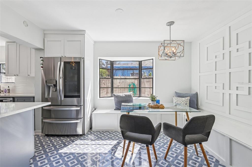A kitchen breakfast nook features a built-in bench, glass table, and patterned blue floor tiles — 4432 W MCCOY STREET, TAMPA, FL