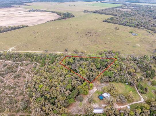 An aerial view shows a wooded lot outlined in red next to a house with a pool — Unassigned STATE ROAD 24, ARCHER, FL
