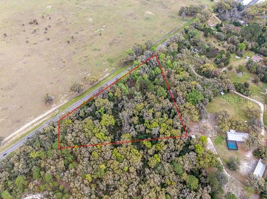 An aerial view shows a triangular plot of wooded land outlined in red near a road — Unassigned STATE ROAD 24, ARCHER, FL