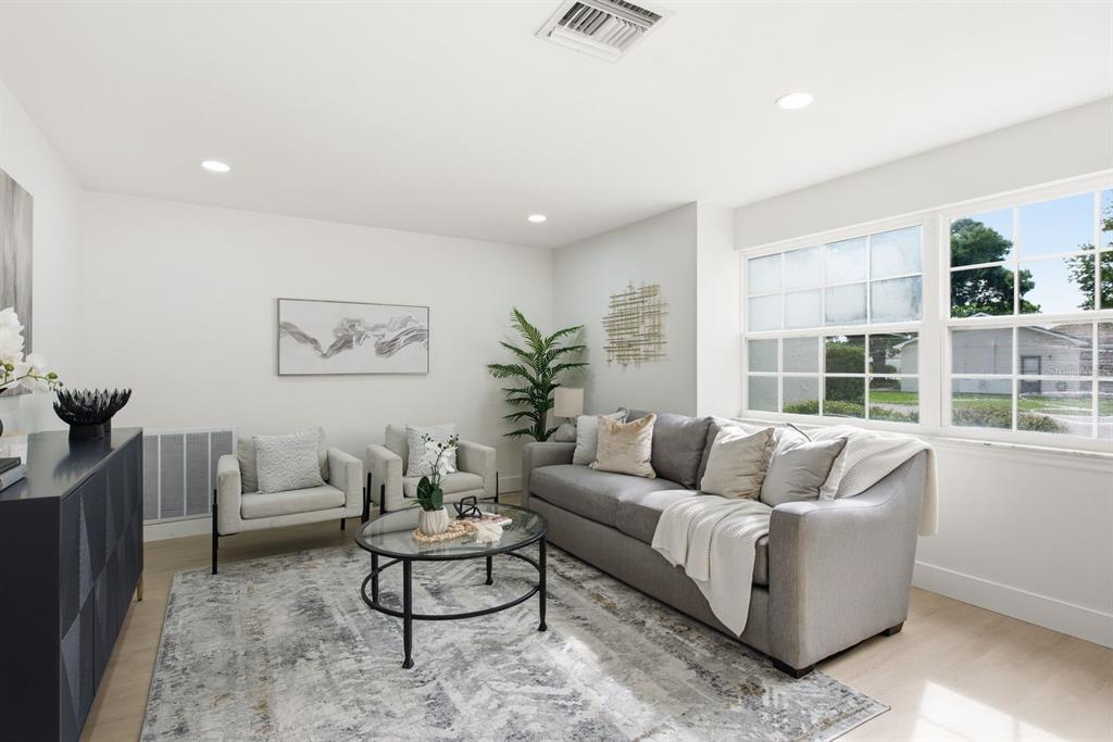 A living room features a grey sofa, two armchairs, a glass coffee table, and windows — 13013 SPICEBOX WAY, HUDSON, FL