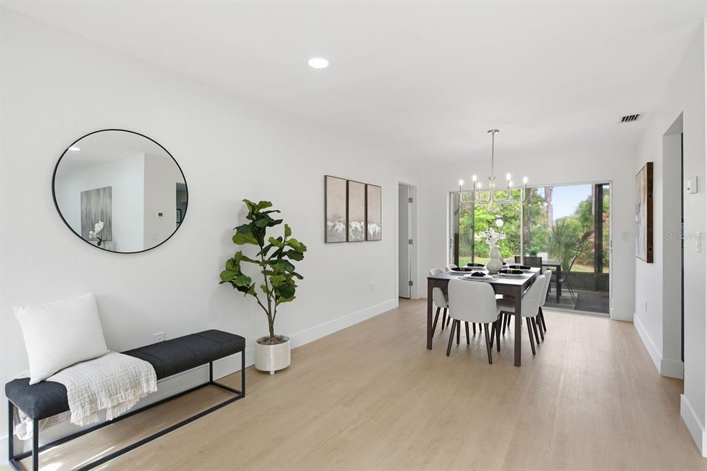 A dining room with light wood floors, a dark bench, a mirror, and a sliding door — 13013 SPICEBOX WAY, HUDSON, FL