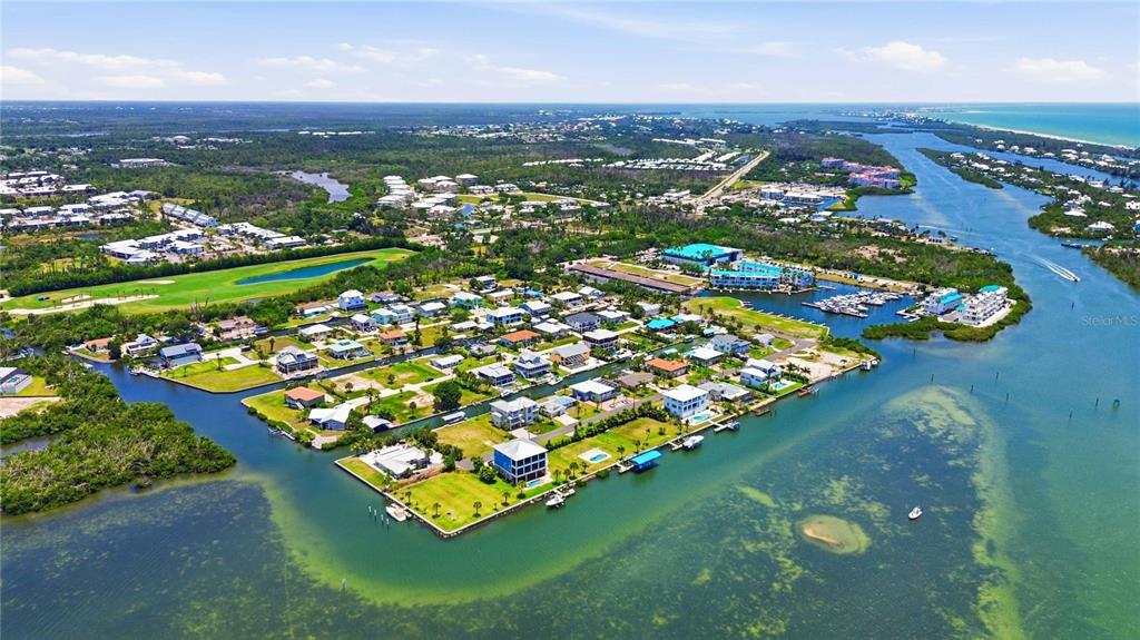 An aerial view shows a coastal residential neighborhood surrounded by water and green space — 10460 MARION STREET, ENGLEWOOD, FL