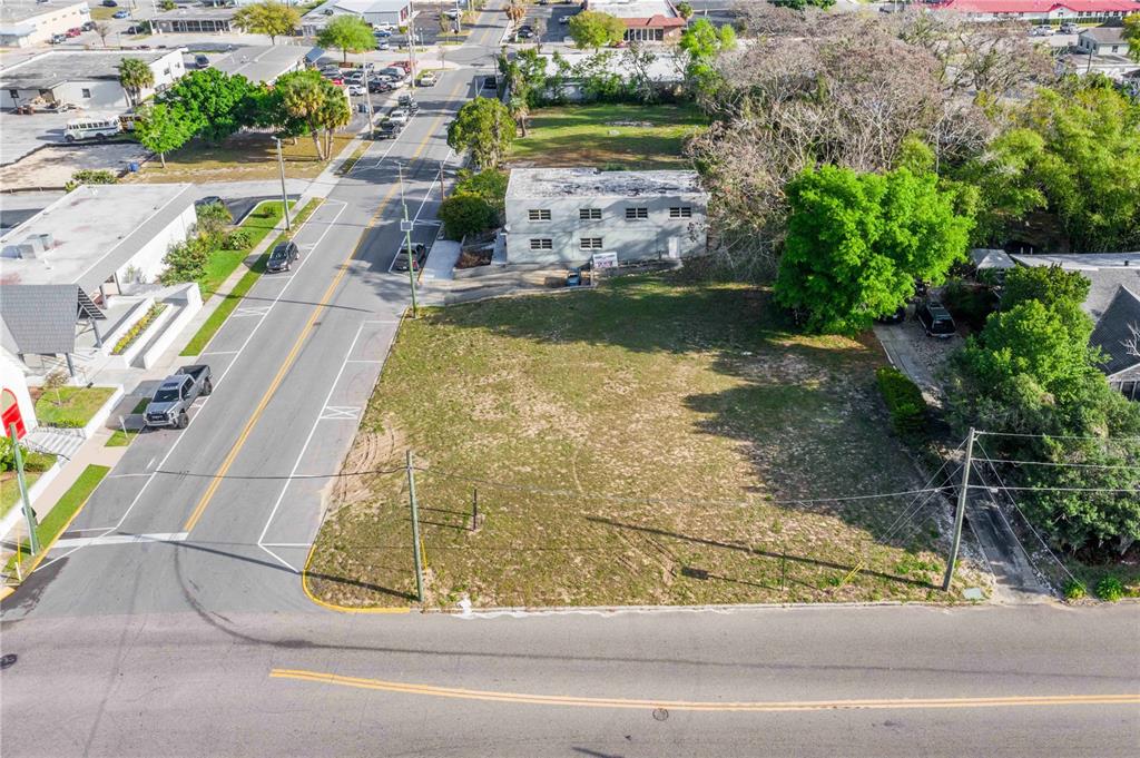 An aerial view shows a vacant, grassy rectangular lot situated between a road and a building — 902 E MAIN STREET, HAINES CITY, FL