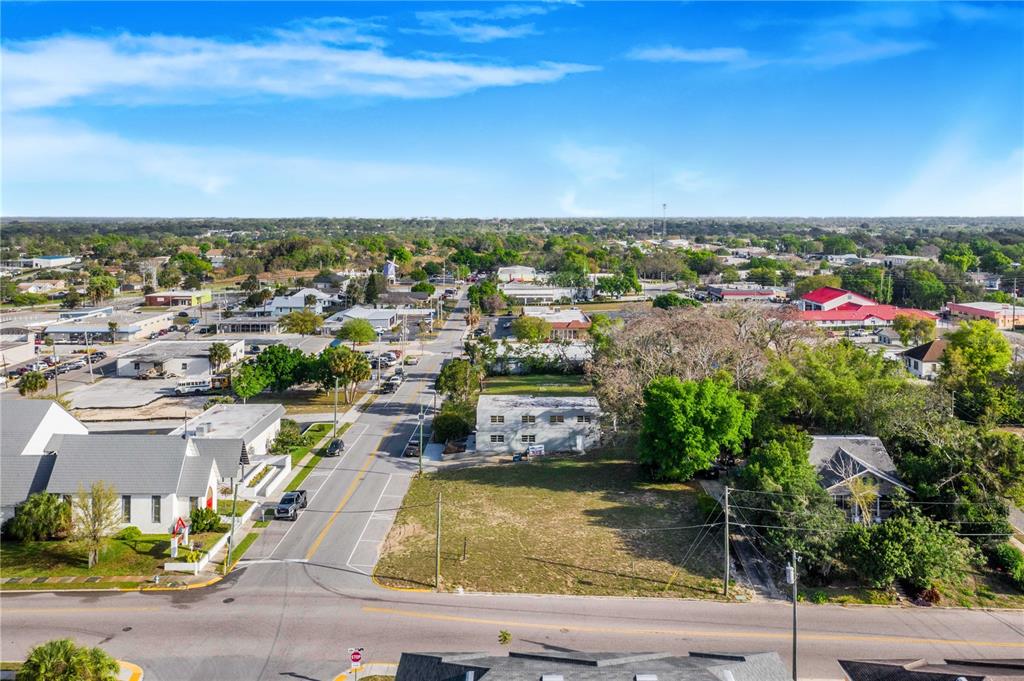 An aerial view shows a vacant lot situated between a small building and a house — 902 E MAIN STREET, HAINES CITY, FL