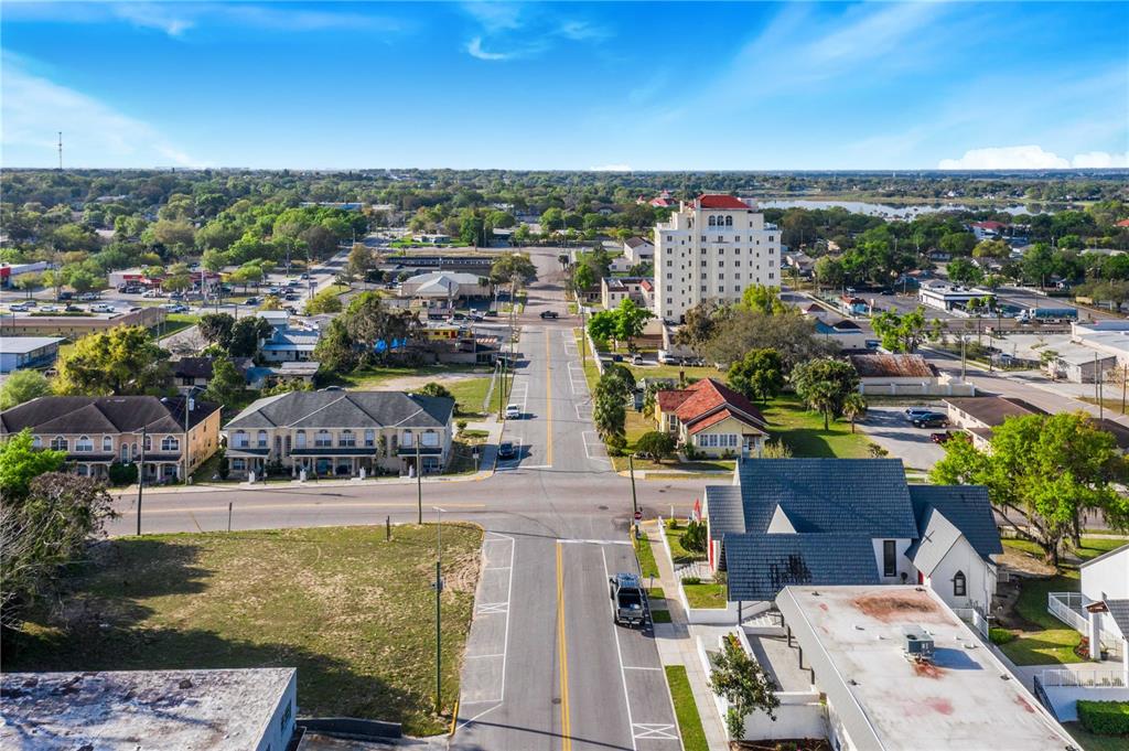 An aerial view shows a street intersection surrounded by residential buildings, a hotel, and trees — 902 E MAIN STREET, HAINES CITY, FL