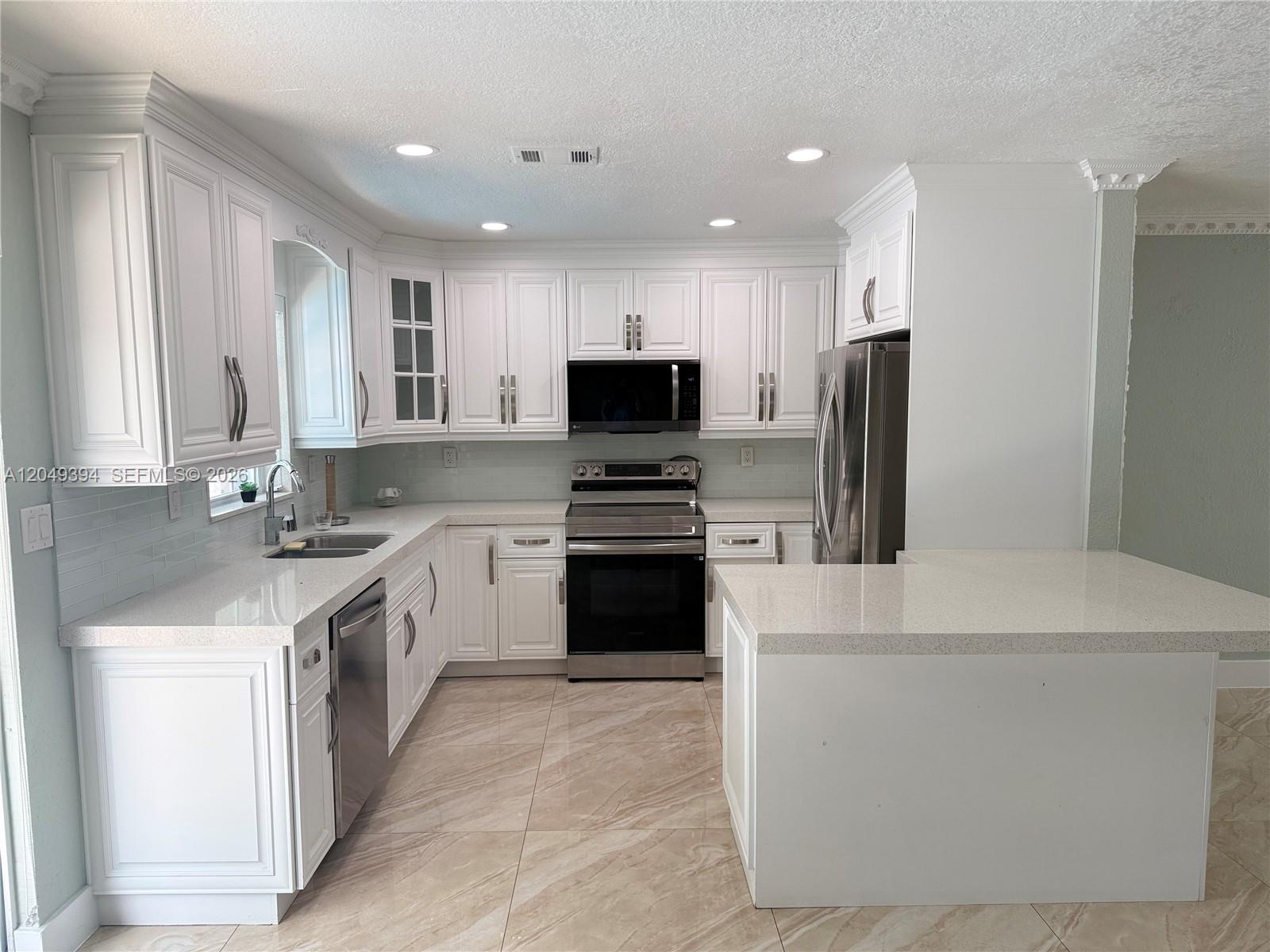 A kitchen features white cabinets, stainless steel appliances, and light-colored countertops and tile flooring — 9675 SW 19th St, Miami FL 33165, MIAMI, FL