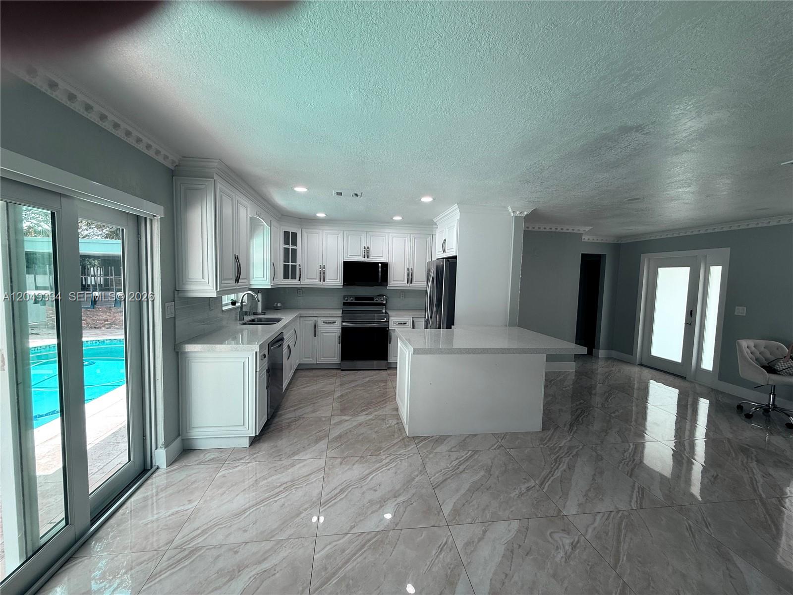 A kitchen with white cabinets, stainless steel appliances, a center island, and marble-look tile flooring — 9675 SW 19th St, Miami FL 33165, MIAMI, FL