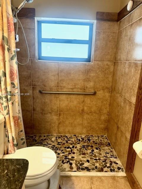 A bathroom features a walk-in shower with stone pebble flooring and tan wall tiles — 1481 SW 7th Ter, Deerfield Beach FL 33441, DEERFIELD BEACH, FL