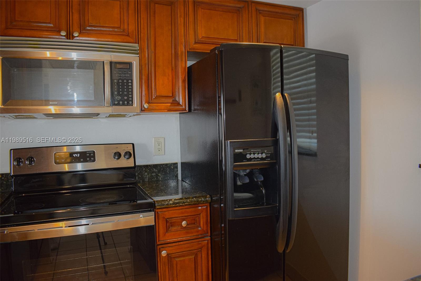 A kitchen features dark wood cabinets, stainless steel appliances, and a black side-by-side refrigerator — 9230 Lagoon Pl # 411, Davie FL 33324, DAVIE, FL