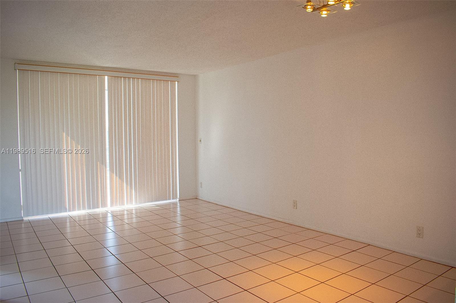 An empty room features white walls, light-colored tile flooring, and vertical blinds over a window — 9230 Lagoon Pl # 411, Davie FL 33324, DAVIE, FL