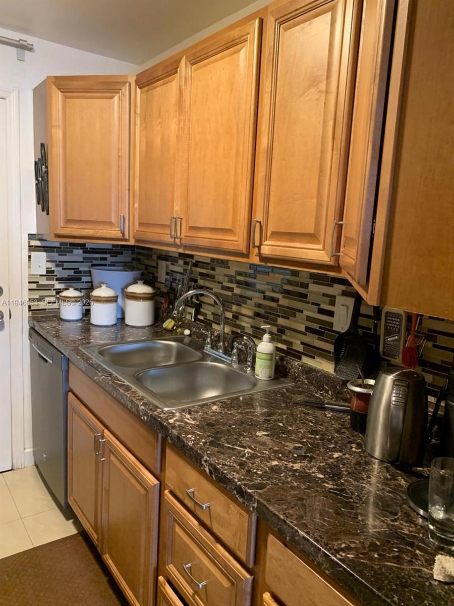 A kitchen features wood cabinets, a dark granite countertop, and a mosaic tile backsplash — 16801 NE 13th Ave # 301, Miami FL 33162, MIAMI, FL