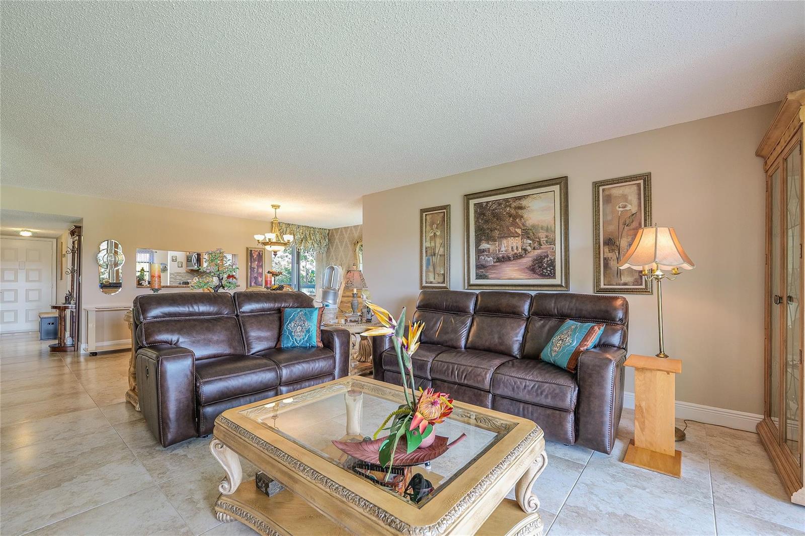 A living room features two brown leather sofas, a glass-topped coffee table, and tile flooring — 3650 Environ Boulevard # 401, Lauderhill FL 33319, LAUDERHILL, FL