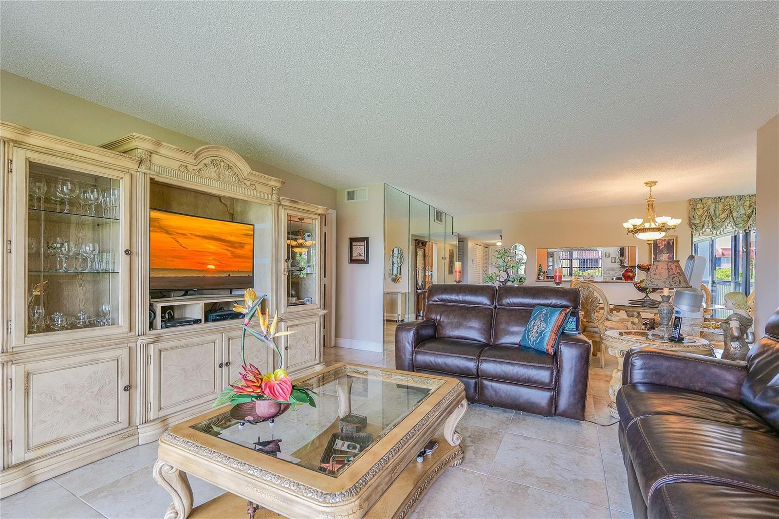 A living room features a large entertainment center, leather sofas, and a glass coffee table — 3650 Environ Boulevard # 401, Lauderhill FL 33319, LAUDERHILL, FL