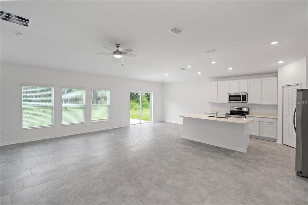 An open-concept kitchen and living area features white cabinetry, a central island, and tile flooring — 4819 WORCHESTER DRIVE, KISSIMMEE, FL