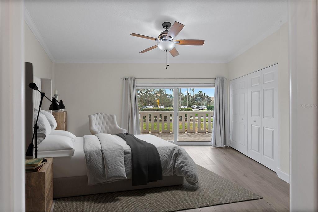 A bedroom with light wood flooring, a ceiling fan, a bed, and a sliding glass door — 1200 N SHORE DRIVE NE UNIT 102, ST PETERSBURG, FL