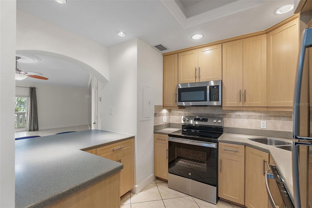 A kitchen features light wood cabinets, stainless steel appliances, and a gray countertop peninsula — 1200 N SHORE DRIVE NE UNIT 102, ST PETERSBURG, FL
