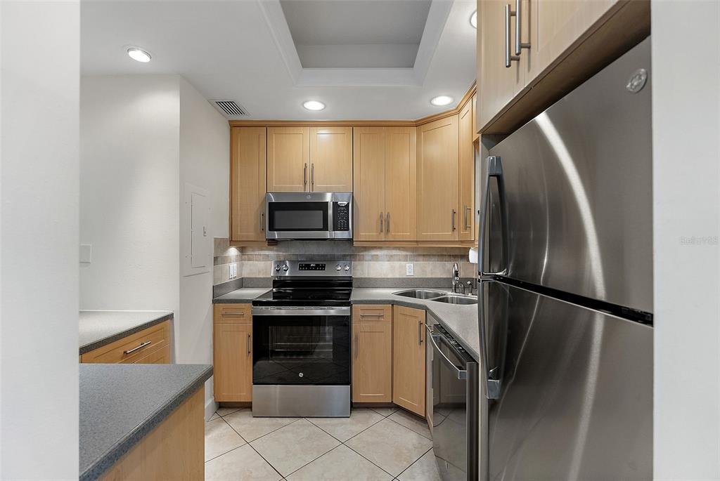 A kitchen features light wood cabinets, stainless steel appliances, and a gray countertop — 1200 N SHORE DRIVE NE UNIT 102, ST PETERSBURG, FL