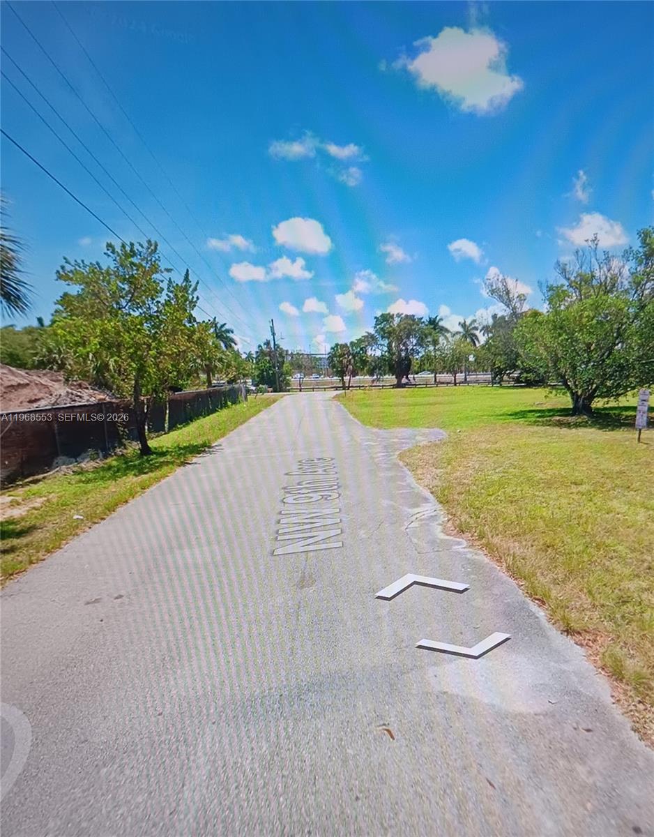 A paved road leads through a grassy area with trees under a blue sky — 0 NW 9th Ave, Pompano Beach FL 33060, POMPANO BEACH, FL