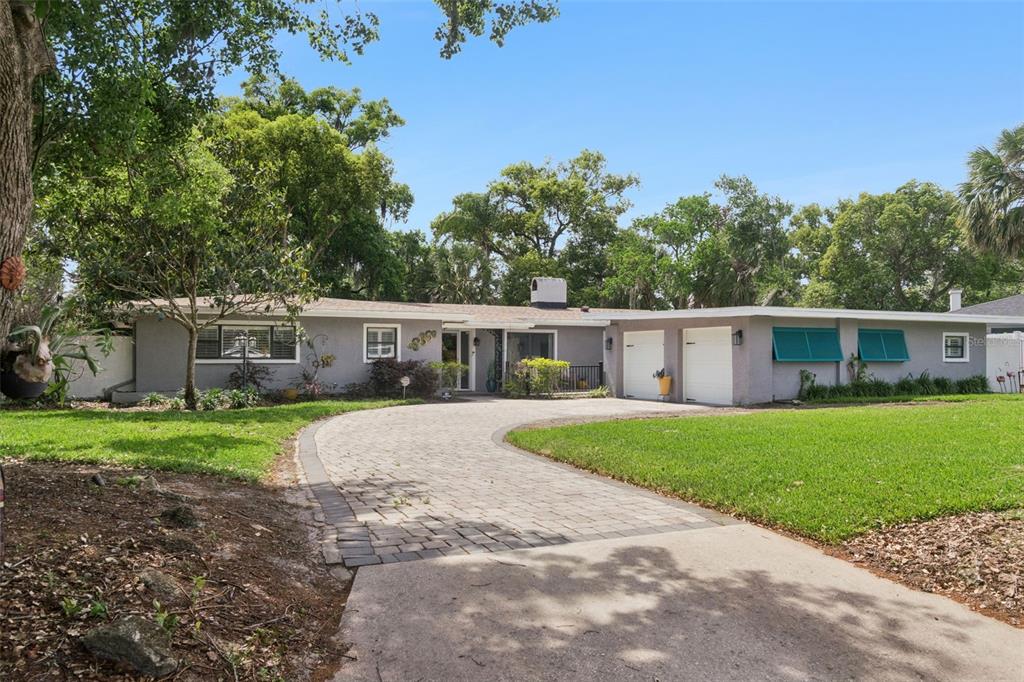 A single-story gray house with a paved driveway, two garage doors, and green window shutters — 140 WIGWAM PLACE, MAITLAND, FL