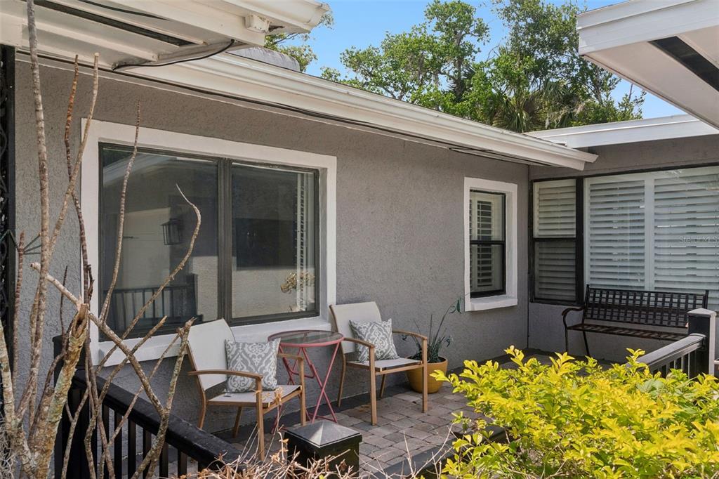 A patio with two chairs, a small table, and a bench sits against a gray house — 140 WIGWAM PLACE, MAITLAND, FL