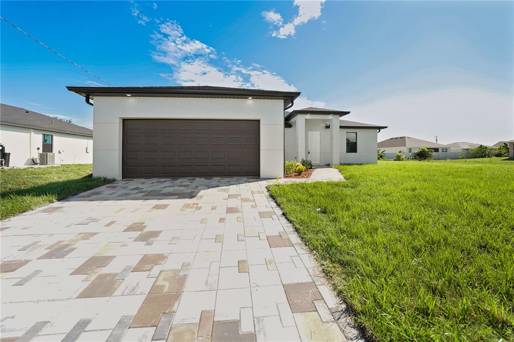 A modern single-story house features a two-car garage and a paved driveway — 2458 NW 9TH TERRACE, CAPE CORAL, FL