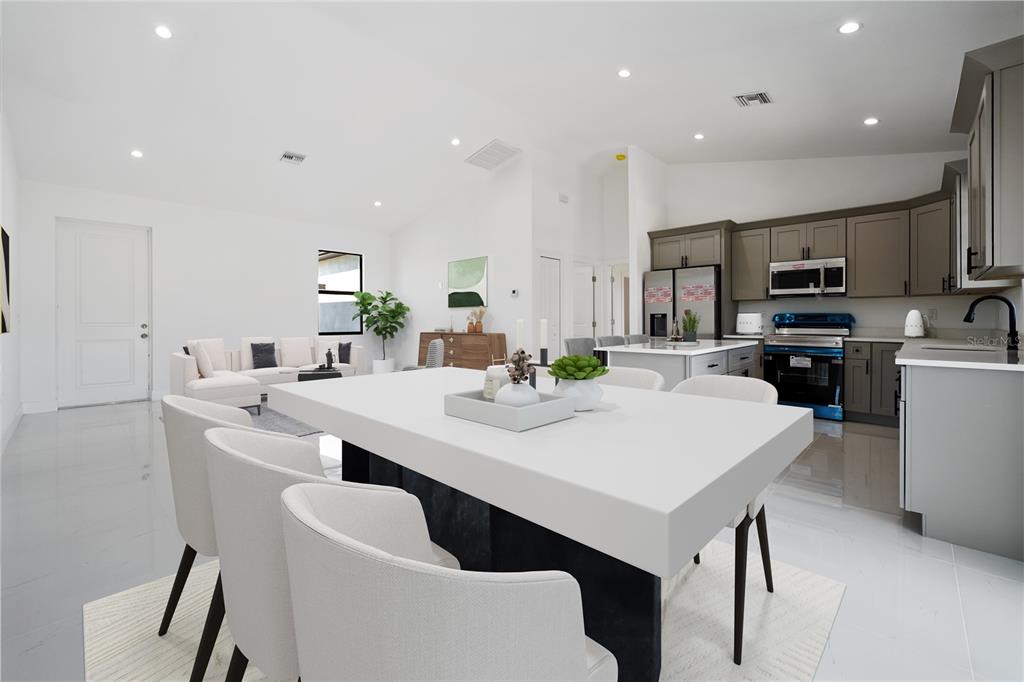 A modern open-concept kitchen and dining area featuring white surfaces, gray cabinetry, and tile flooring — 2458 NW 9TH TERRACE, CAPE CORAL, FL