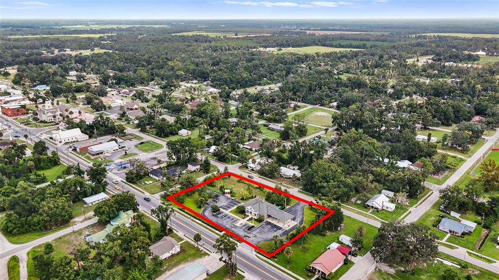An aerial view shows a commercial building with a parking lot outlined in red — 130 NE CLYDE AVENUE, MAYO, FL