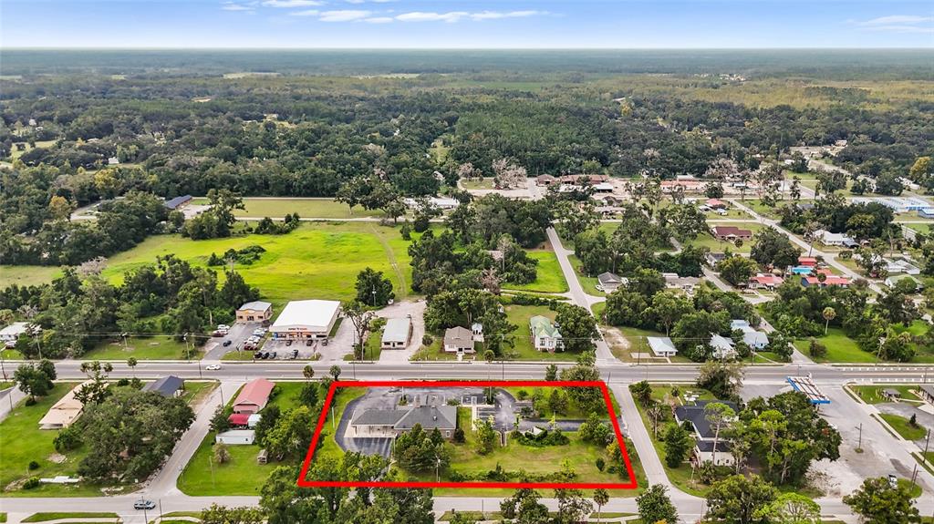 An aerial view shows a commercial building with a parking lot outlined in red — 130 NE CLYDE AVENUE, MAYO, FL