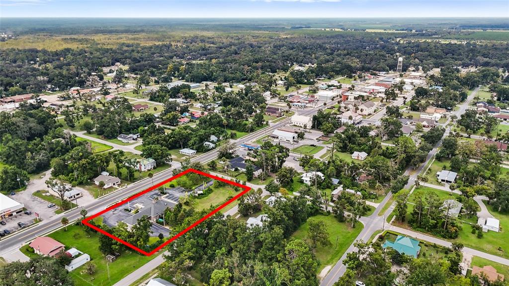 An aerial view shows a commercial property outlined in red within a small town — 130 NE CLYDE AVENUE, MAYO, FL