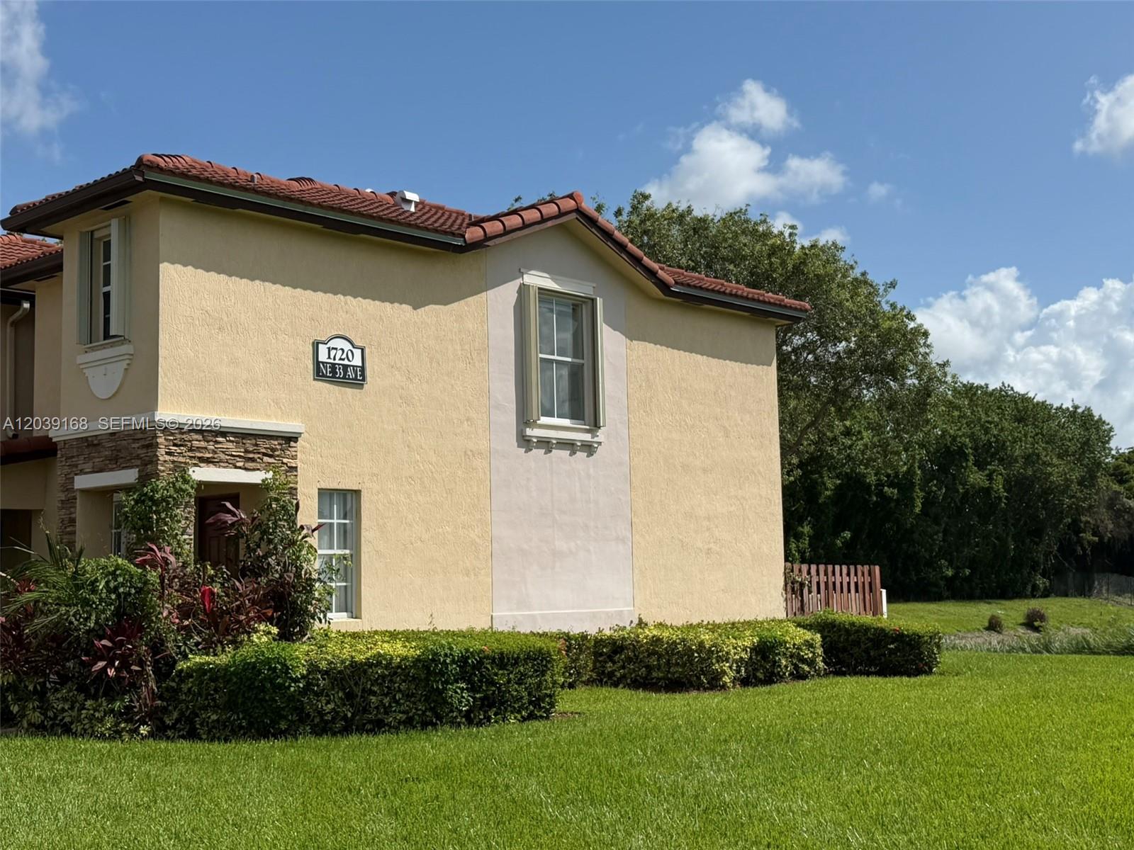 A two-story stucco building with a tiled roof, stone accents, and manicured landscaping — 1720 NE 33rd Ave # 5, Homestead FL 33033, HOMESTEAD, FL