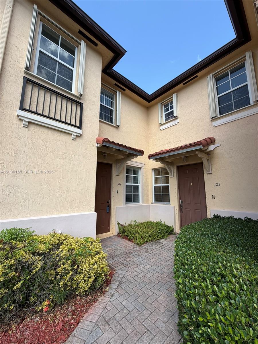 Two adjacent residential unit entrances feature brown doors, small tiled awnings, and a brick walkway — 1720 NE 33rd Ave # 5, Homestead FL 33033, HOMESTEAD, FL