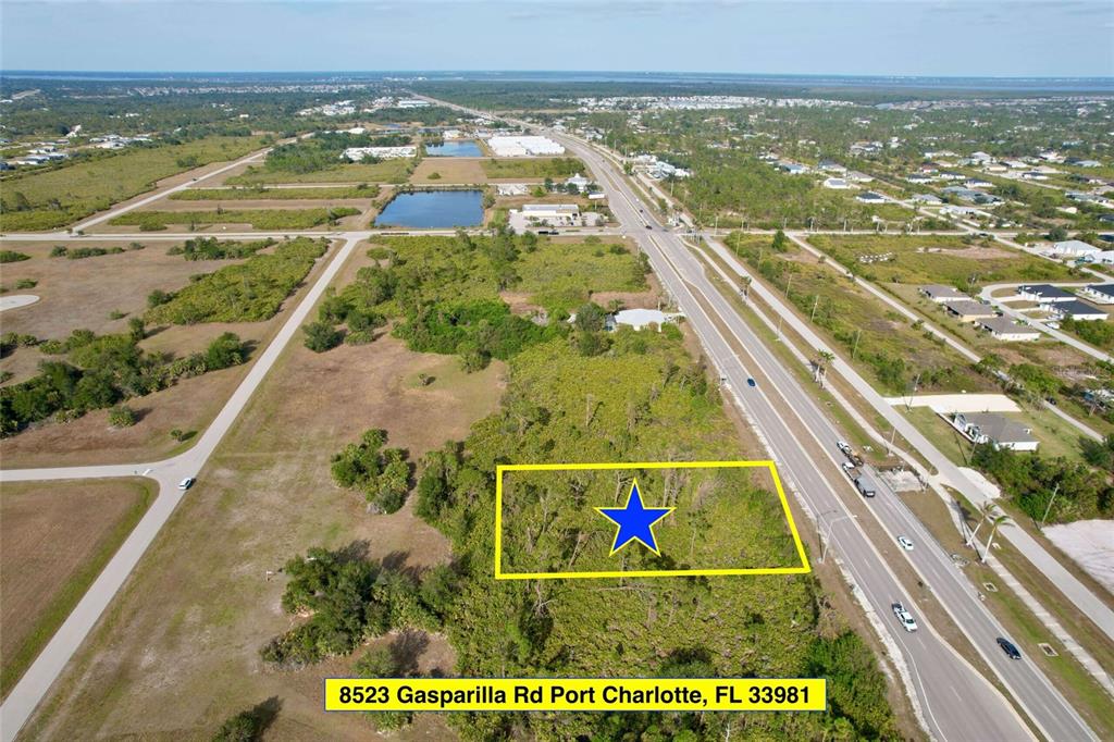 An aerial view shows a rectangular plot of land highlighted in yellow beside a highway — 8523 GASPARILLA ROAD, PORT CHARLOTTE, FL