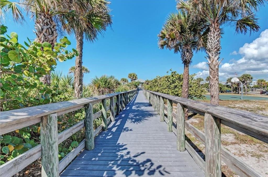 A wooden boardwalk leads through palm trees toward a distant structure near a tennis court — 11 BIRCH COURT, PLACIDA, FL