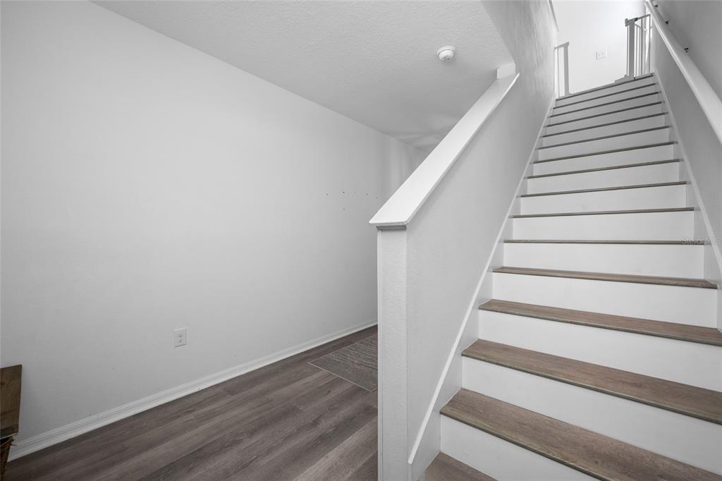 A staircase with wood-look treads and white risers sits beside a white-walled entryway — 16826 SECRET MEADOW DRIVE, ODESSA, FL