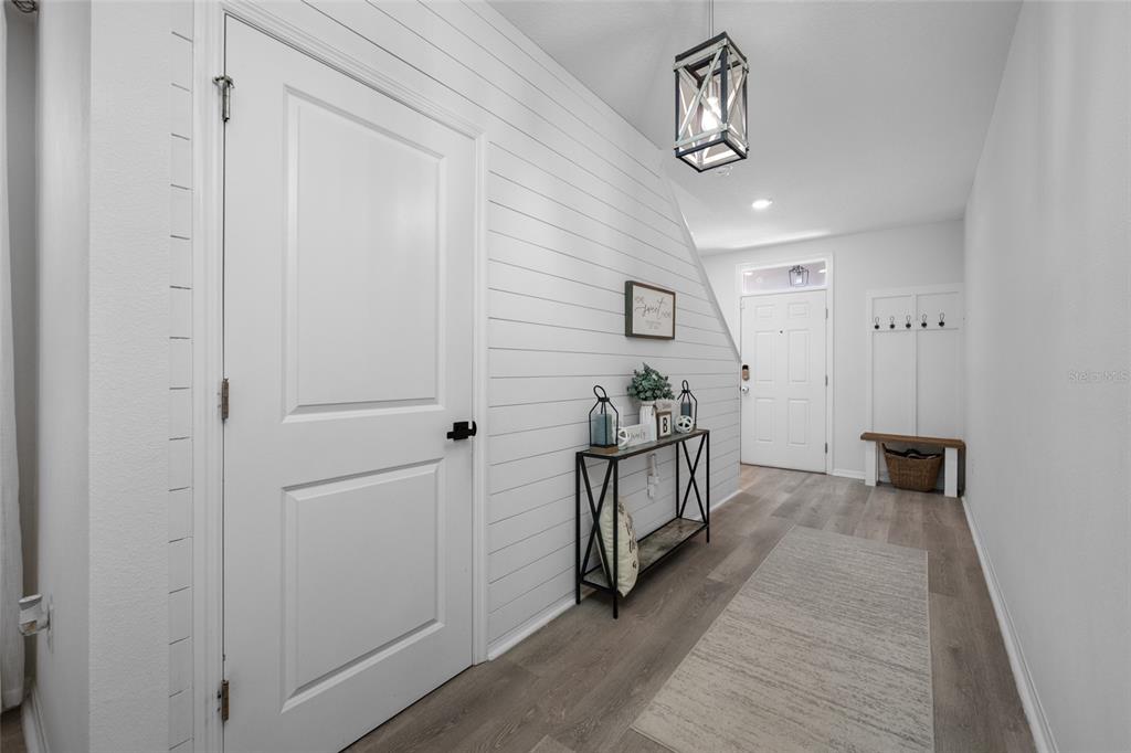 A bright entryway features shiplap walls, wood-look flooring, a console table, and a coat rack — 16826 SECRET MEADOW DRIVE, ODESSA, FL
