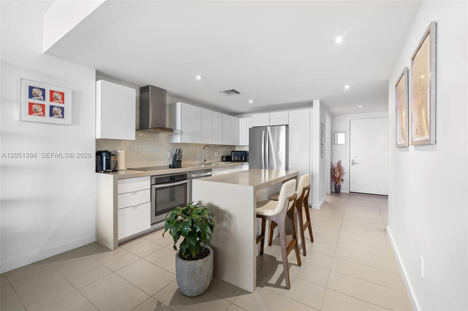 A modern kitchen features white cabinetry, stainless steel appliances, a central island, and tile flooring — 1600 NE 1st Ave # 3111, Miami FL 33132, MIAMI, FL