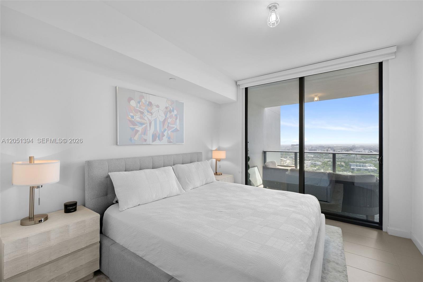 A bedroom features a gray upholstered bed, white bedding, and a balcony with city views — 1600 NE 1st Ave # 3111, Miami FL 33132, MIAMI, FL