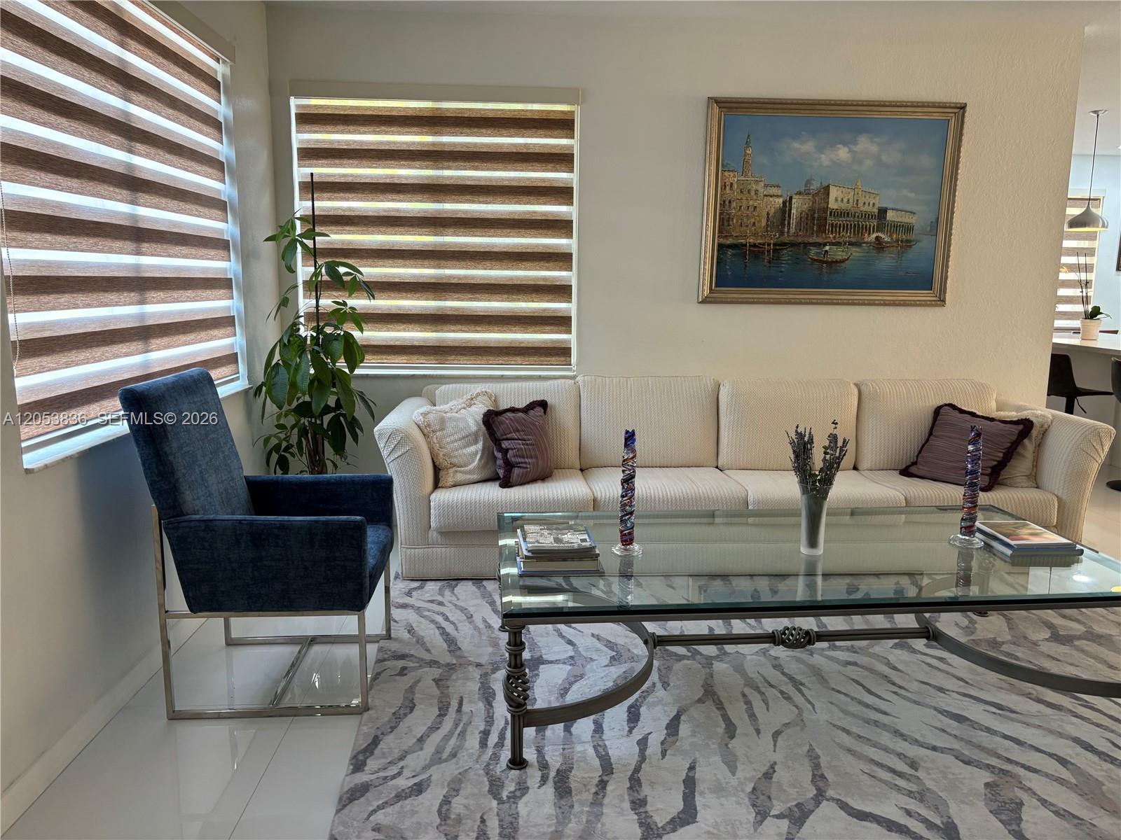 A living room features a white sofa, a blue armchair, and a glass coffee table — WESTON, FL