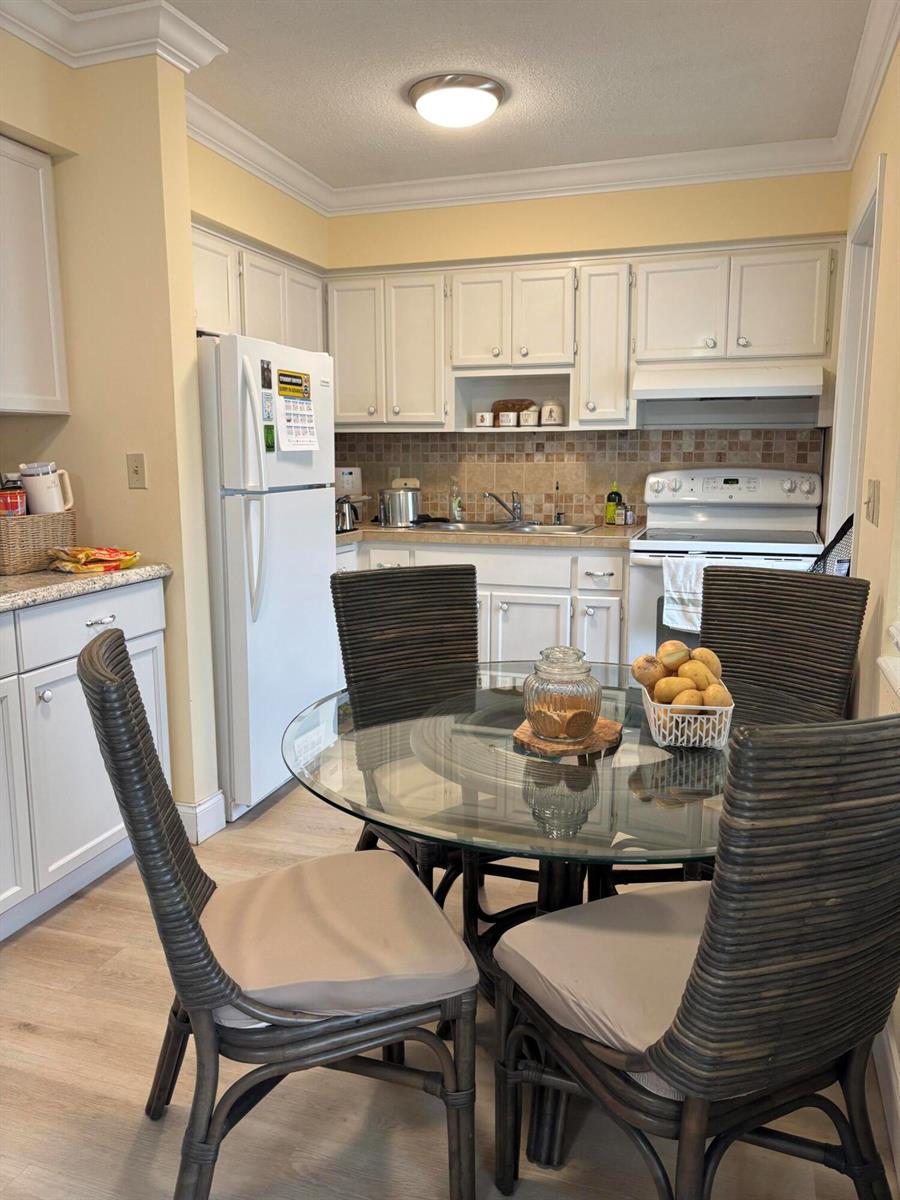 A kitchen features white cabinets, a glass-topped dining table, and wicker chairs — 2121 NE 42ND Court # 202C, Lighthouse Point FL 33064, LIGHTHOUSE POINT, FL