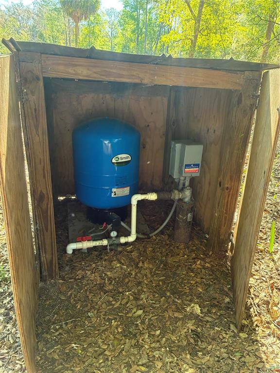 A blue water pressure tank and electrical control box are housed inside a wooden shed — 24533 PINK PANTHER ROAD, PAISLEY, FL