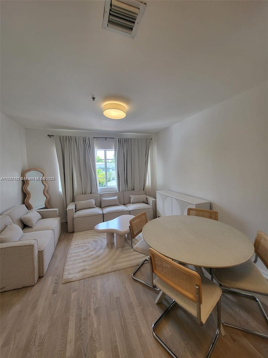 A living and dining area features light-colored furniture, a round table, and wood flooring — 810 7th St # 206, Miami Beach FL 33139, MIAMI BEACH, FL