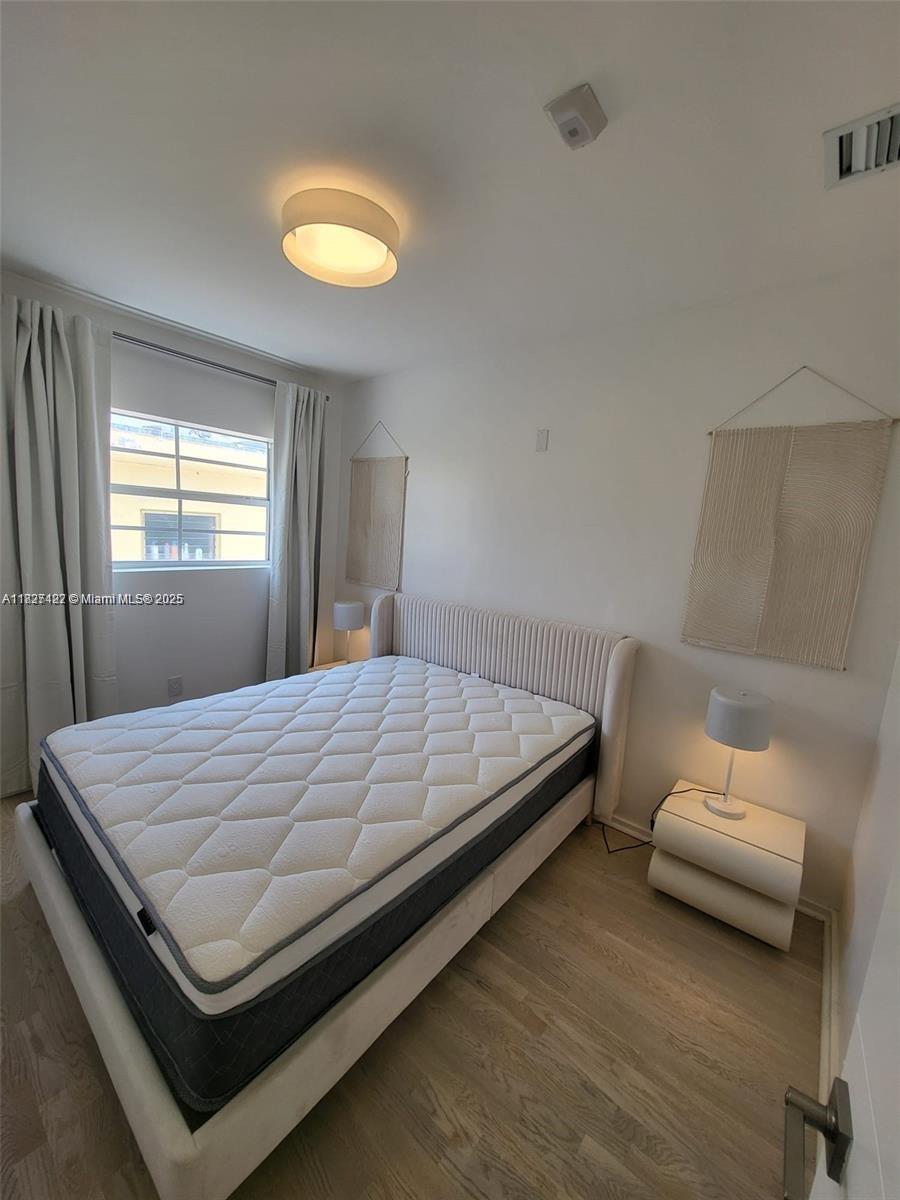 A bedroom features a platform bed, two nightstands with lamps, wall hangings, and light wood flooring — 810 7th St # 206, Miami Beach FL 33139, MIAMI BEACH, FL