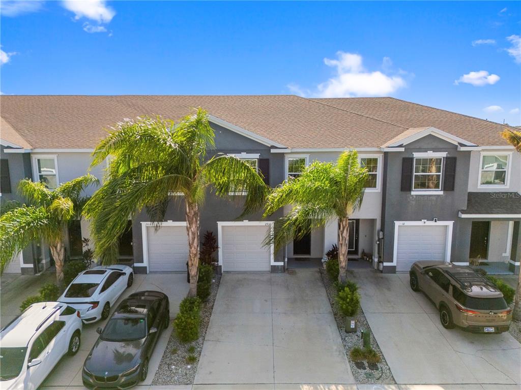 An exterior view of a row of townhouses with attached garages and palm trees — 2914 SUNCOAST BLEND DRIVE, ODESSA, FL