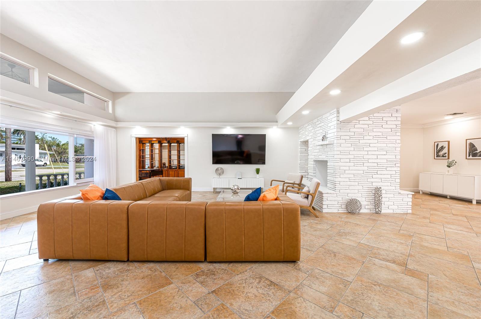 A spacious living room features a large tan sectional, white stone fireplace, and tile flooring — 2500 NE 199th St, Miami FL 33180, MIAMI, FL