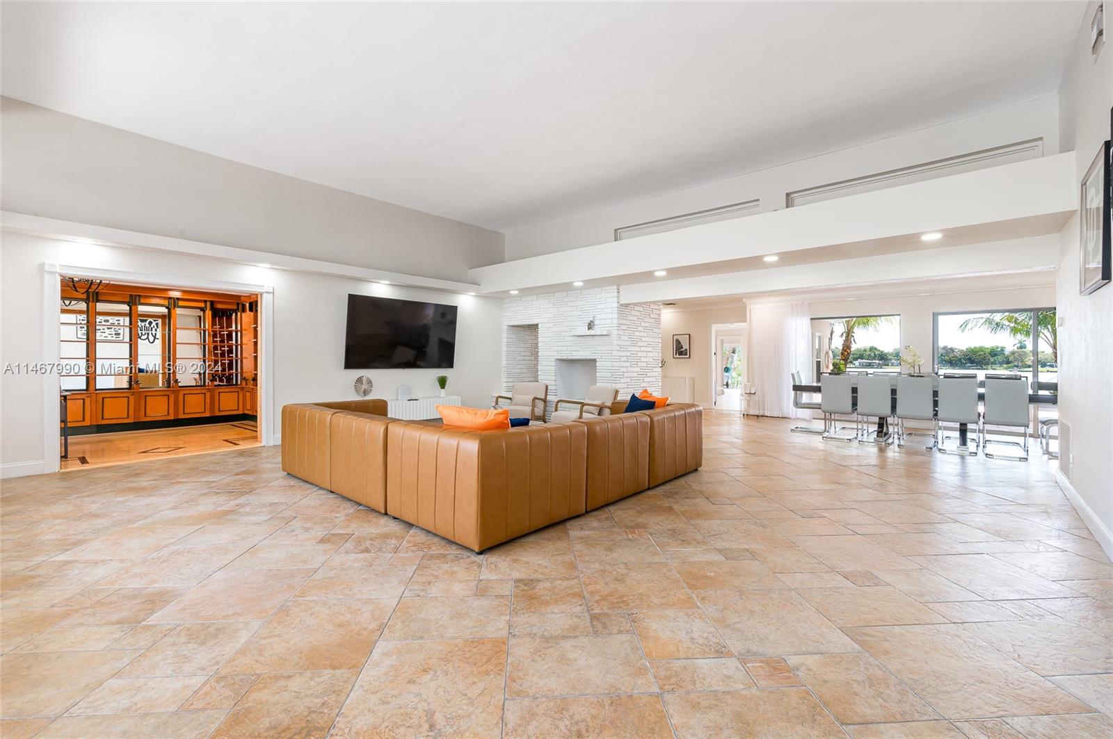 A spacious living room features a tan sectional sofa, a fireplace, and a dining area — 2500 NE 199th St, Miami FL 33180, MIAMI, FL