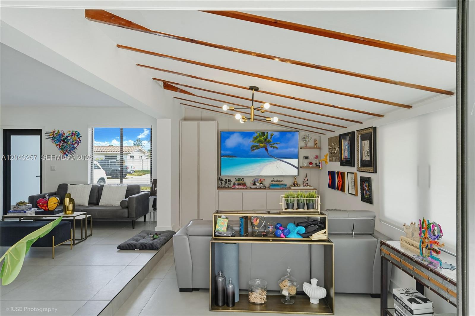 A living room features a vaulted ceiling with exposed wooden beams and a television wall — 2450 NE 209th Ter, Miami FL 33180, MIAMI, FL