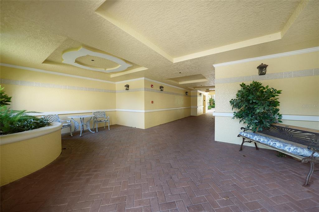 A covered outdoor patio features a brick floor, yellow walls, and decorative seating areas — 255 W END DRIVE UNIT 3306, PUNTA GORDA, FL