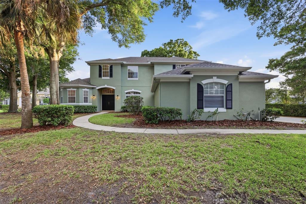 A two-story green stucco house features a front walkway, dark shutters, and mature trees — 1545 CHERRY RIDGE DRIVE, LAKE MARY, FL